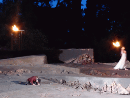Herald and the torch being lighted by a woman at the stage of the Greek Theatre at the Parco Archeologico della Neapolis park, during the play `Agamemnon` by Aeschylus