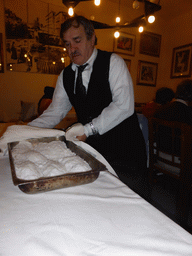 Waiter preparing salted fish at the Trattoria Archimede restaurant at the Via Mario Gemmellaro street