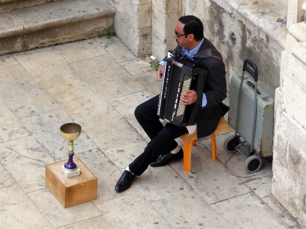 Street musician in front of the Chiesa di Santa Lucia alla Badia church at the Piazza Duomo square, viewed from the balcony of the Palazzo Borgia del Casale palace