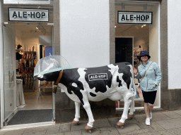 Miaomiao with a cow statue in front of the ALE-HOP store at the Calle Real de la Plaza street