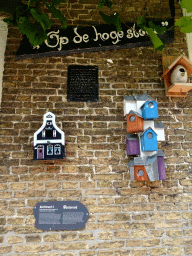 Birdhouses at the facade of a house at the Kerkstraat street at Oosterend, with explanation