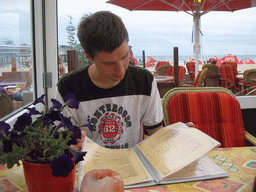 Tim looking at the menu at a beach pavilion at the Strandweg street of Scheveningen, with a view on the Pier of Scheveningen