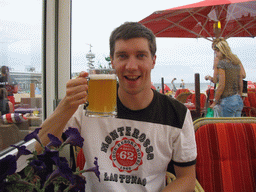 Tim with a beer at a beach pavilion at the Strandweg street of Scheveningen, with a view on the Pier of Scheveningen