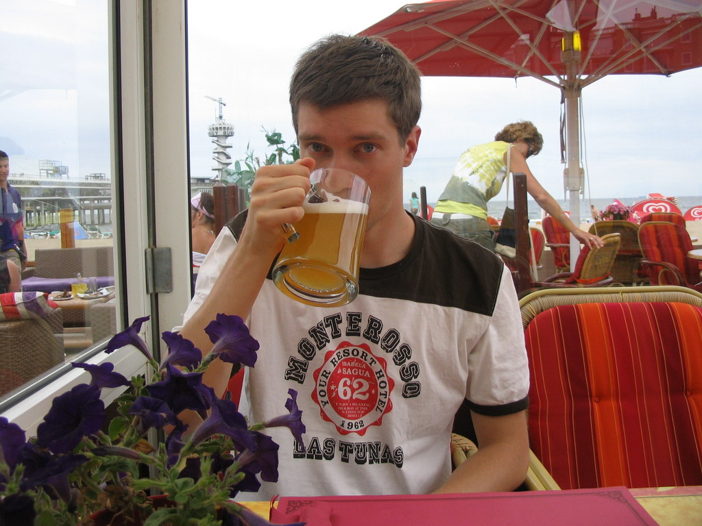 Tim with a beer at a beach pavilion at the Strandweg street of Scheveningen, with a view on the Pier of Scheveningen