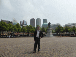 Miaomiao`s father at the Plein square with the statue of prince Willem I and the skyscrapers in the city center