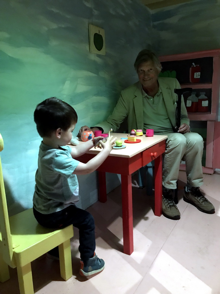 Max and his grandfather at the table in the home of Kikker at the `Kikker is hier!` exhibition at the second floor of the Natuurmuseum Brabant