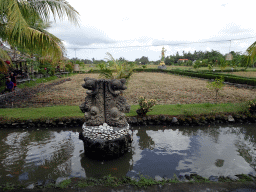 Pond with fountain, rice fields and statue at the back side of the Bebek Joni Restaurant