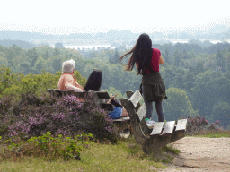 People on benches on the top of the Posbank hill, with a view on the southwest side with the IJssel river