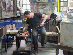 Man making glass figure in a workplace at the Calle Bressagio street at the Murano islands