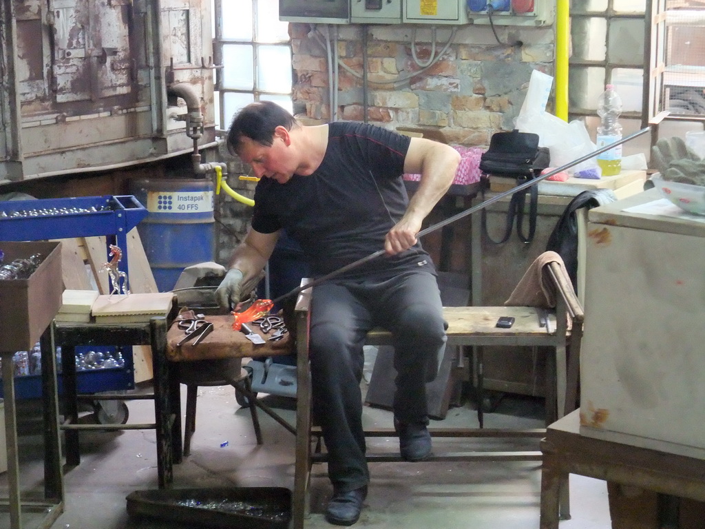 Man making glass figure in a workplace at the Calle Bressagio street at the Murano islands