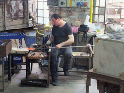 Man making glass figure in a workplace at the Calle Bressagio street at the Murano islands
