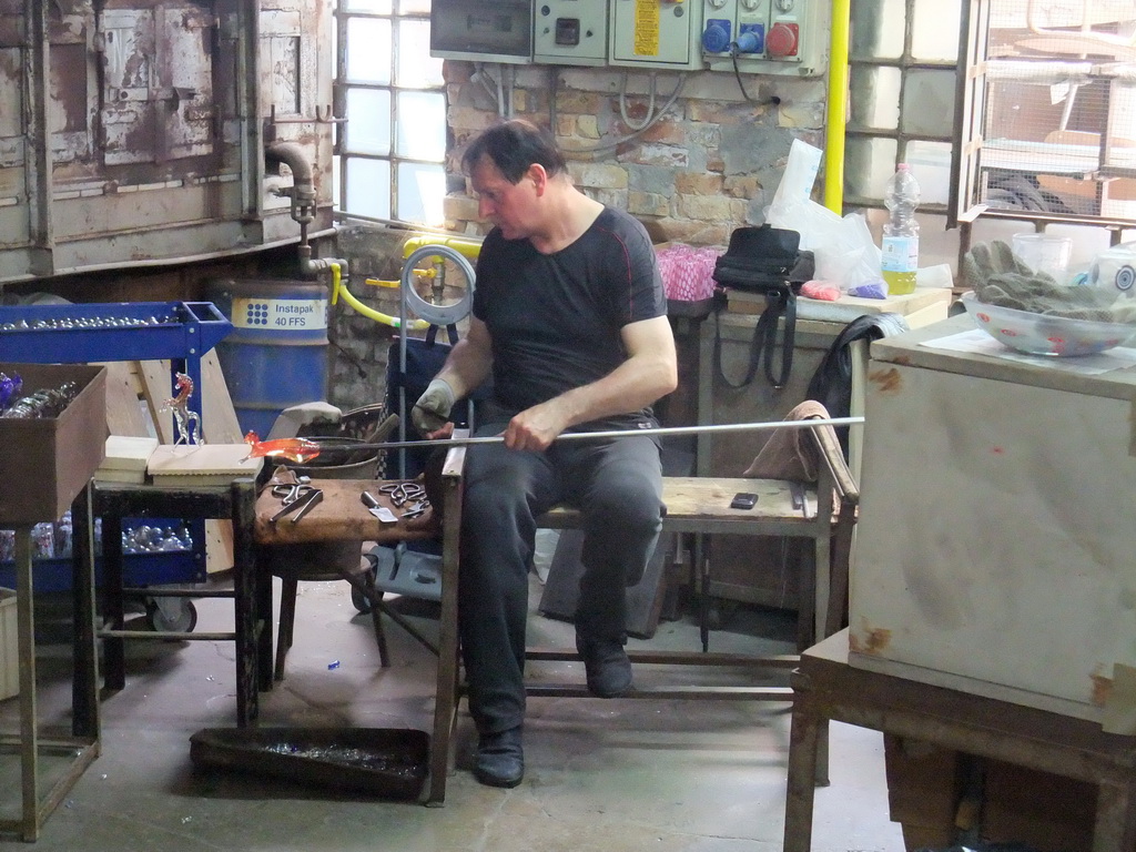 Man making glass figure in a workplace at the Calle Bressagio street at the Murano islands