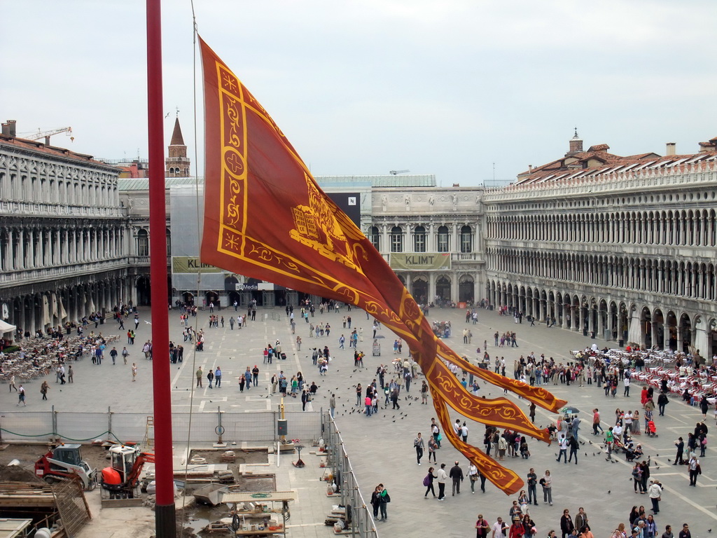 Venetian flag and the Piazza San Marco square with the Procuratie Nuove building, the Napoleonic Wing of the Procuraties building and the Procuratie Vecchie building, viewed from the loggia of the Basilica di San Marco church