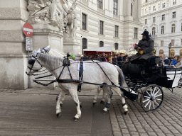 Horses and carriage entering the In Der Burg courtyard of the Hofburg palace from the Michaelerplatz square