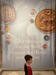 Max in front of a poster of the exhibition `Around the World in 80 Coins` at the second floor of the Kunsthistorisches Museum Wien