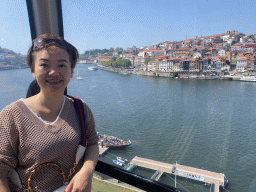 Miaomiao at the Gaia Cable Car, with a view on boats on the Douro river and Porto with the Cais da Estiva street