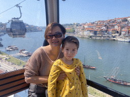 Miaomiao and Max at the Gaia Cable Car, with a view on boats and the Ponte da Arrábida bridge over the Douro river and Porto with the Cais da Estiva street