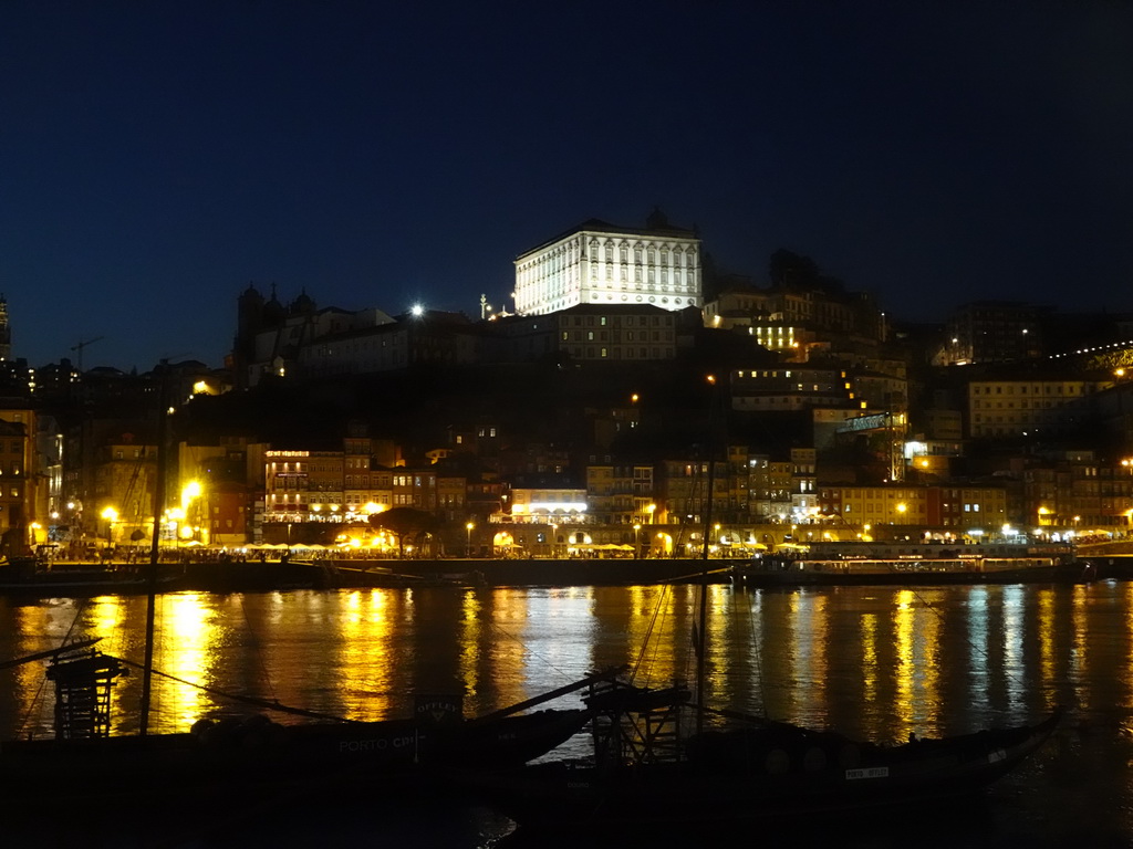 Boats on the Douro river and Porto with the Cais da Ribeira street and the Paço Episcopal do Porto palace, viewed from the Avenida de Diogo Leite street, by night