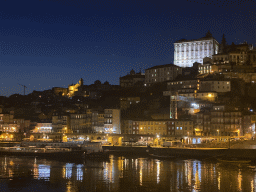 Boats on the Douro river and Porto with the Cais da Ribeira street, the Igreja de Nossa Senhora da Vitória church and the Paço Episcopal do Porto palace, viewed from the Avenida de Diogo Leite street, by night