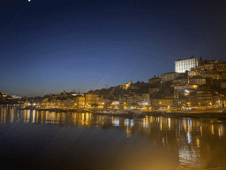 Boats on the Douro river and Porto with the Cais da Estiva and Cais da Ribeira streets, the Igreja de Nossa Senhora da Vitória church and the Paço Episcopal do Porto palace, viewed from the Avenida de Diogo Leite street, by night