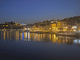 Boats on the Douro river and Porto with the Cais da Estiva and Cais da Ribeira streets, viewed from the lower level of the Ponte Luís I bridge, by night