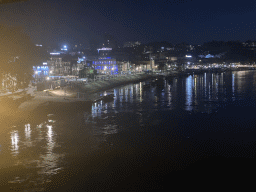 Boats on the Douro river and the Avenida de Diogo Leite street, viewed from the lower level of the Ponte Luís I bridge, by night