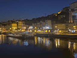 Boats on the Douro river and Porto with the Cais da Ribeira street, viewed from the lower level of the Ponte Luís I bridge, by night