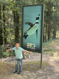 Max with a sign with a photo of a Penguin at the entrance road to the Zoo Santo Inácio