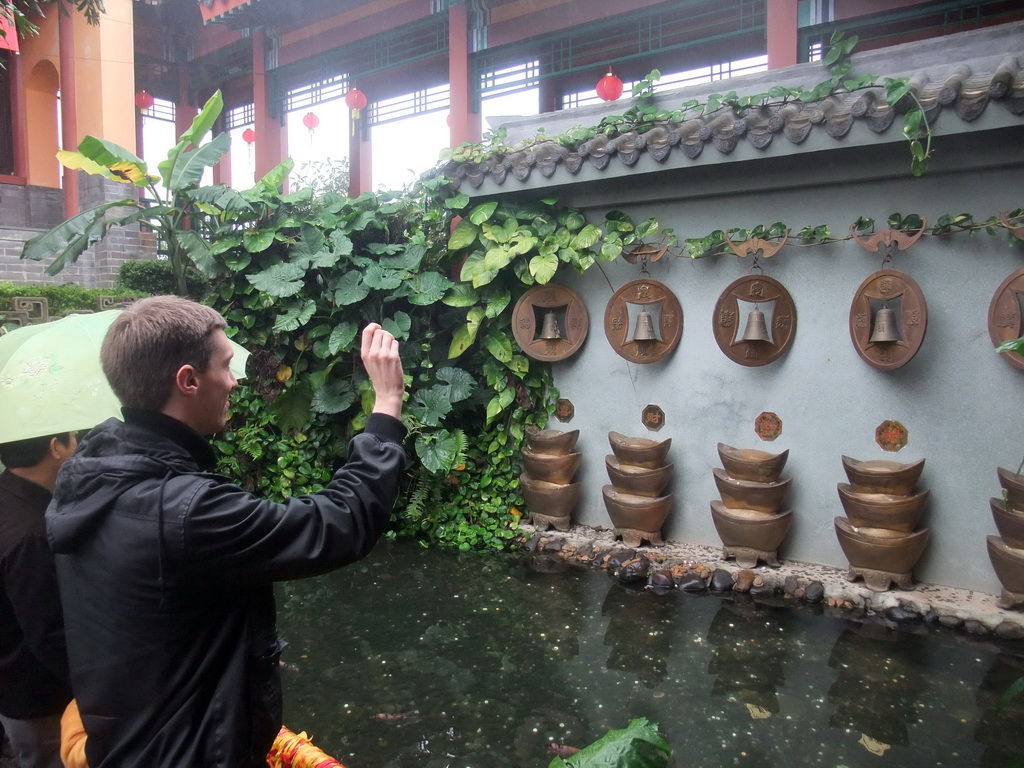 Tim throwing a coin at the buddhist bells at the Yuchan Palace at the Hainan Wenbifeng Taoism Park
