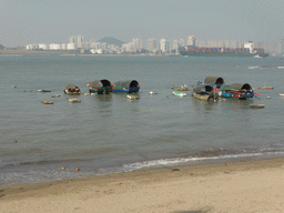 The beach at the west side of Gulangyu Island, boats in Xiamen Bay and skyscrapers at the Haicang district