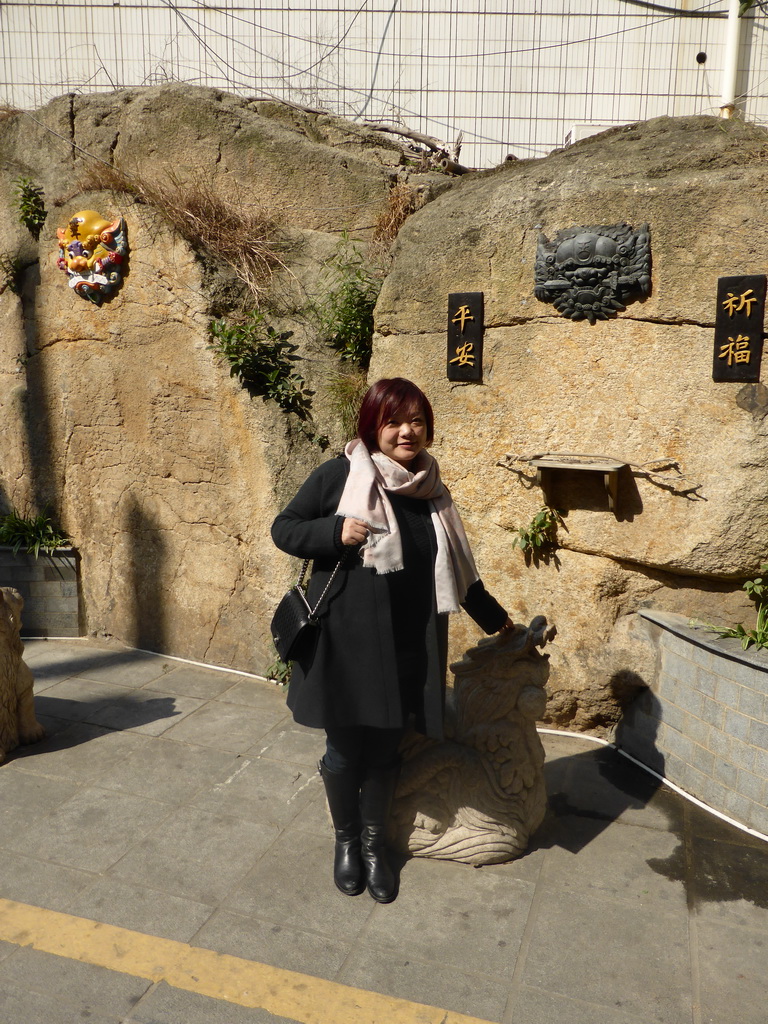 Miaomiao with masks on a wall at the Mintai Characteristic Food Street