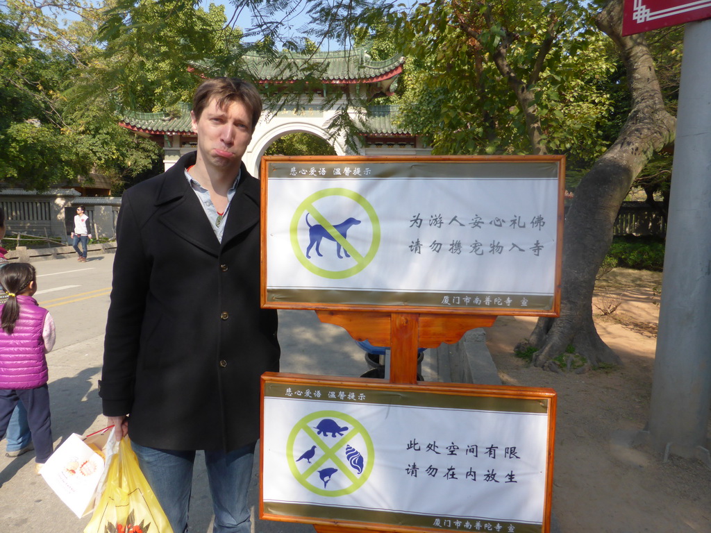 Tim with two signs at the entrance gate to the Nanputuo Temple