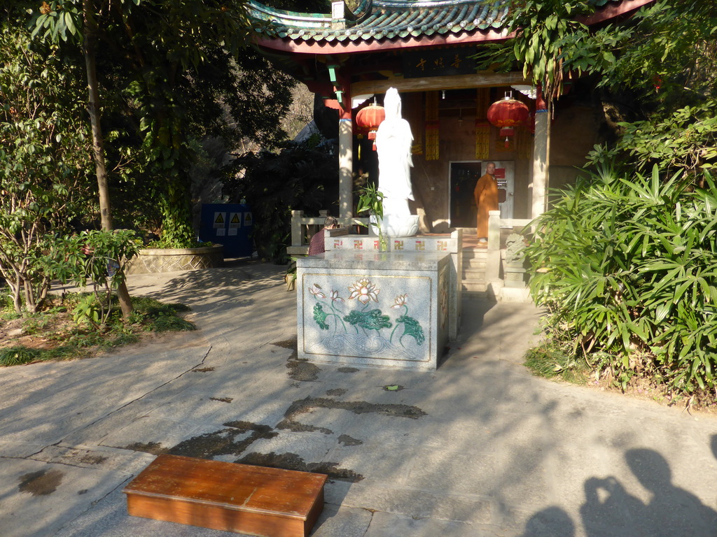 Statue, altar and monk in front of the Puzhao Temple at the back side of the Nanputuo Temple