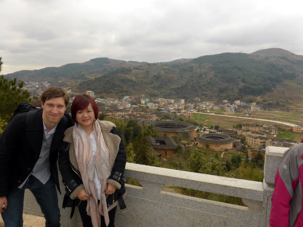 Tim and Miaomiao at the Yongding Scenic Area viewing point, with a view on the Qiaofu Lou, Chengqi Lou, Shize Lou and Beichen Lou buildings of the Gaobei Tulou Cluster