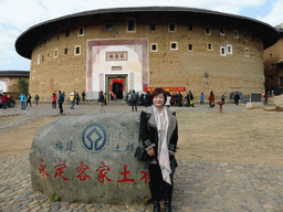 Miaomiao and a rock with the UNESCO World Heritage inscription in front of the Chengqi Lou building of the Gaobei Tulou Cluster