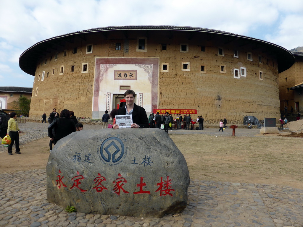 Tim with our photograph and a rock with the UNESCO World Heritage inscription in front of the Chengqi Lou building of the Gaobei Tulou Cluster