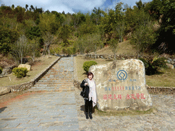 Miaomiao at the rock with inscription of the AAAAA-rating near the entrance to the Yongding Scenic Area with the Gaobei Tulou Cluster