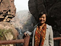 Miaomiao at the bridge at the Red Stone Gorge at the Mount Yuntaishan Global Geopark, with a view on the river and waterfall