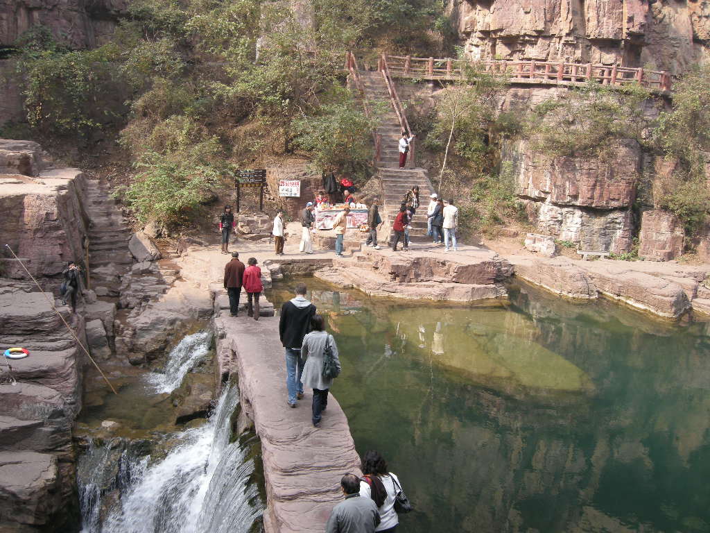 Tim and Miaomiao at the bridge over the waterfall at the Red Stone Gorge at the Mount Yuntaishan Global Geopark, viewed from the mountainside path