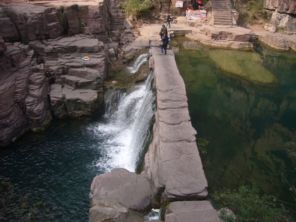 River and bridge over the waterfall at the Red Stone Gorge at the Mount Yuntaishan Global Geopark, viewed from the mountainside path