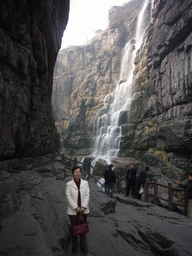 Miaomiao`s mother at the mountainside path at the Red Stone Gorge at the Mount Yuntaishan Global Geopark, with a view on the waterfall