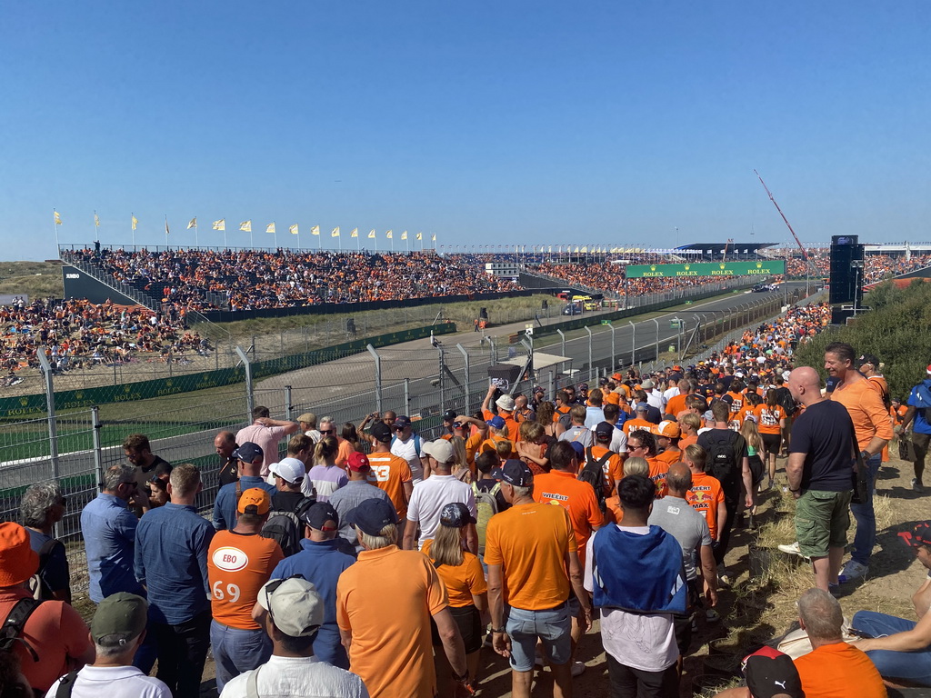 People doing the Paddock Club Tour at the straight between turns 12 and 13 and fans at the Arena-Out Grandstand and Arena Grandstands 2 and 3 at Circuit Zandvoort