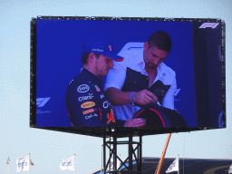 TV screen with Max Verstappen and Rico Verhoeven at the pit straight at Circuit Zandvoort, viewed from the Eastside Grandstand 3, right after the Formula 1 Qualification Session 3