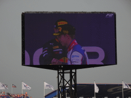 TV screen with Richard Verschoor and Ayumu Iwasa at the main stage at Circuit Zandvoort, viewed from the Eastside Grandstand 3, during the podium ceremony of the Formula 2 Feature Race