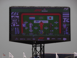 TV screen with Felipe Drugovich, Richard Verschoor and Ayumu Iwasa at the main stage at Circuit Zandvoort, viewed from the Eastside Grandstand 3, during the podium ceremony of the Formula 2 Feature Race