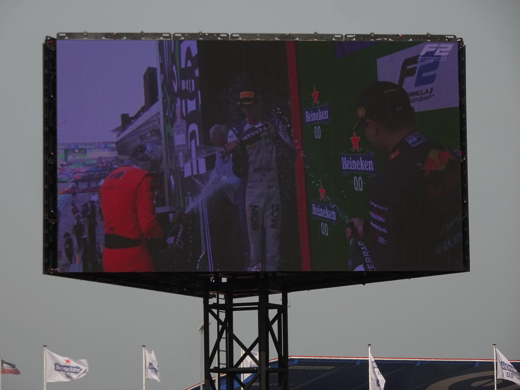 TV screen with Felipe Drugovich, Richard Verschoor and Ayumu Iwasa at the main stage at Circuit Zandvoort, viewed from the Eastside Grandstand 3, during the podium ceremony of the Formula 2 Feature Race