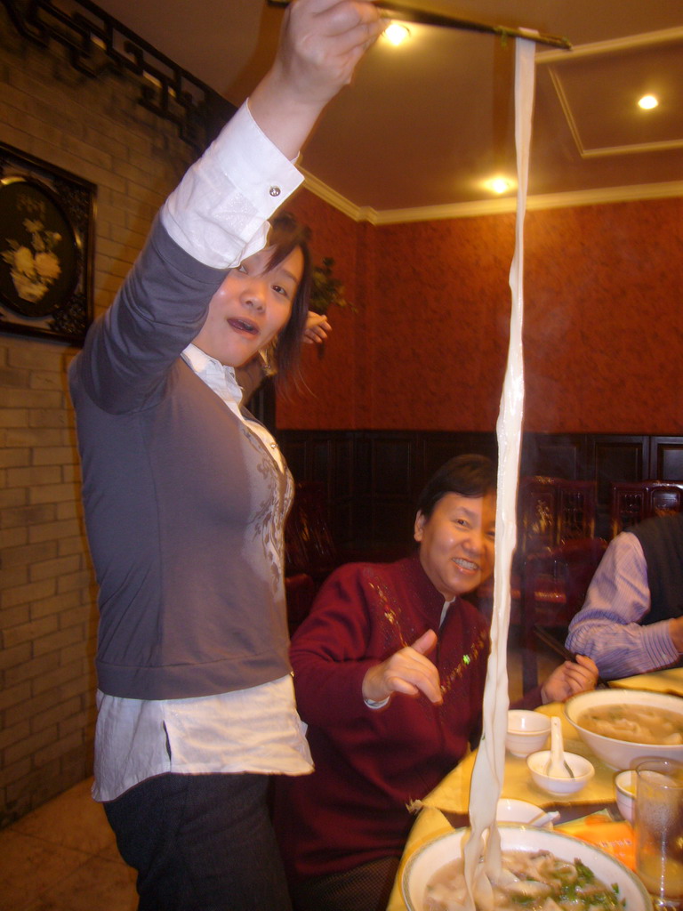 Miaomiao and her mother with noodles in a restaurant in the city center