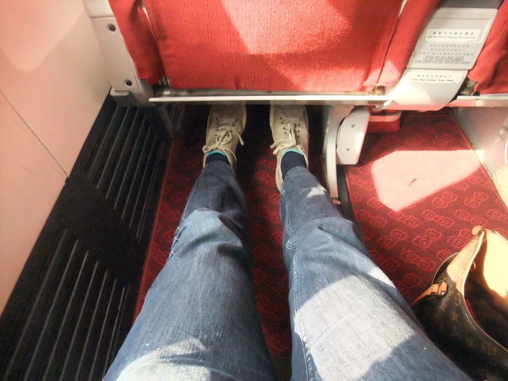 Tim`s legs in the first class seat in the airplane to Haikou