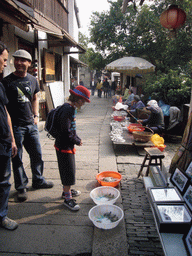 People selling fishes, turtles and art on a street at the Zhouzhuang Water Town