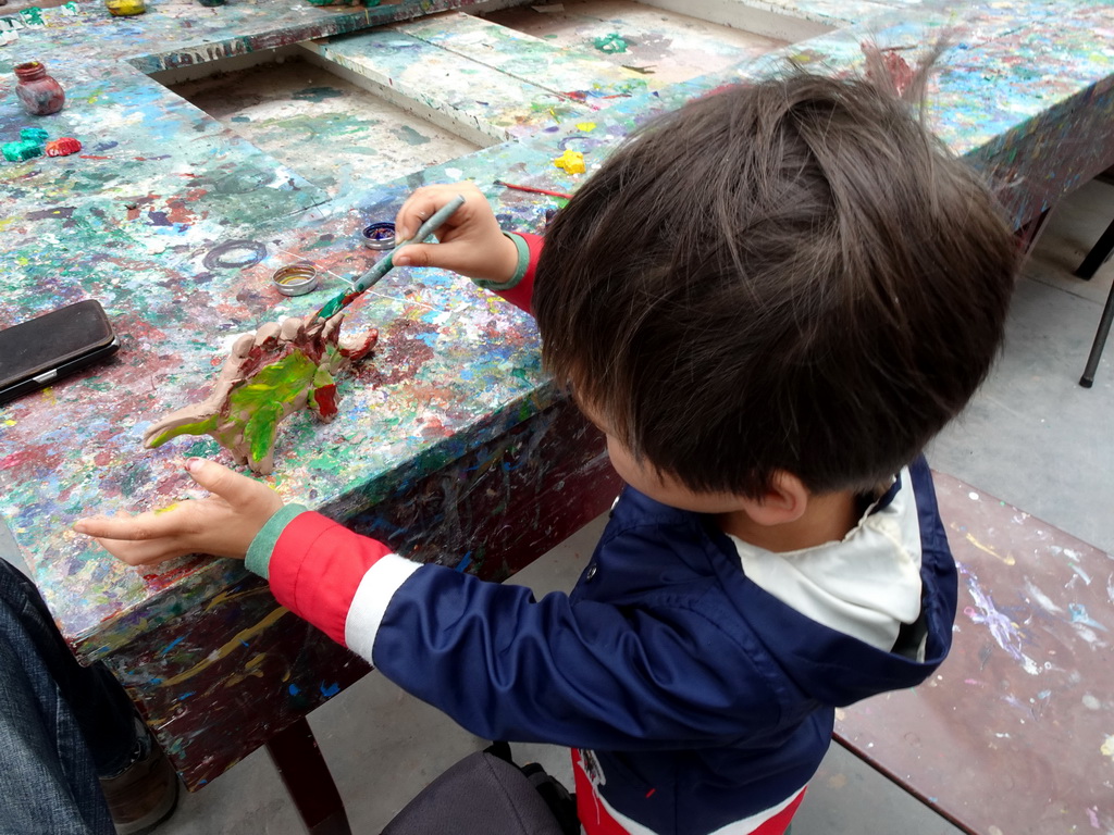 Max painting a Dinosaur statuette made from clay at the PaleoLab at Dinoland Zwolle